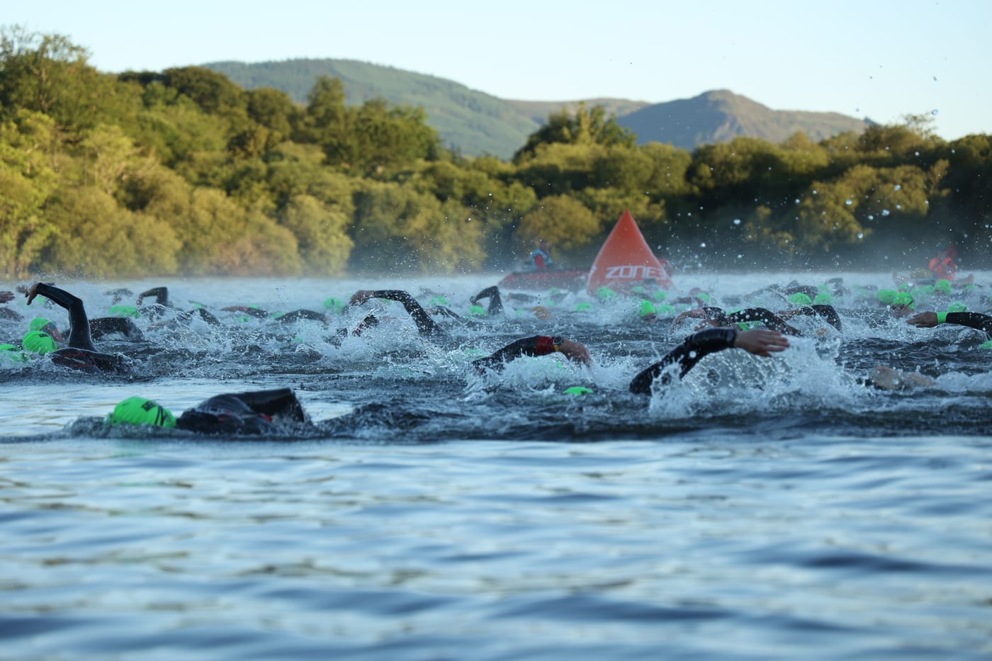Wetsuited swimmers at the Lakesman mass swim start with the fells behind
